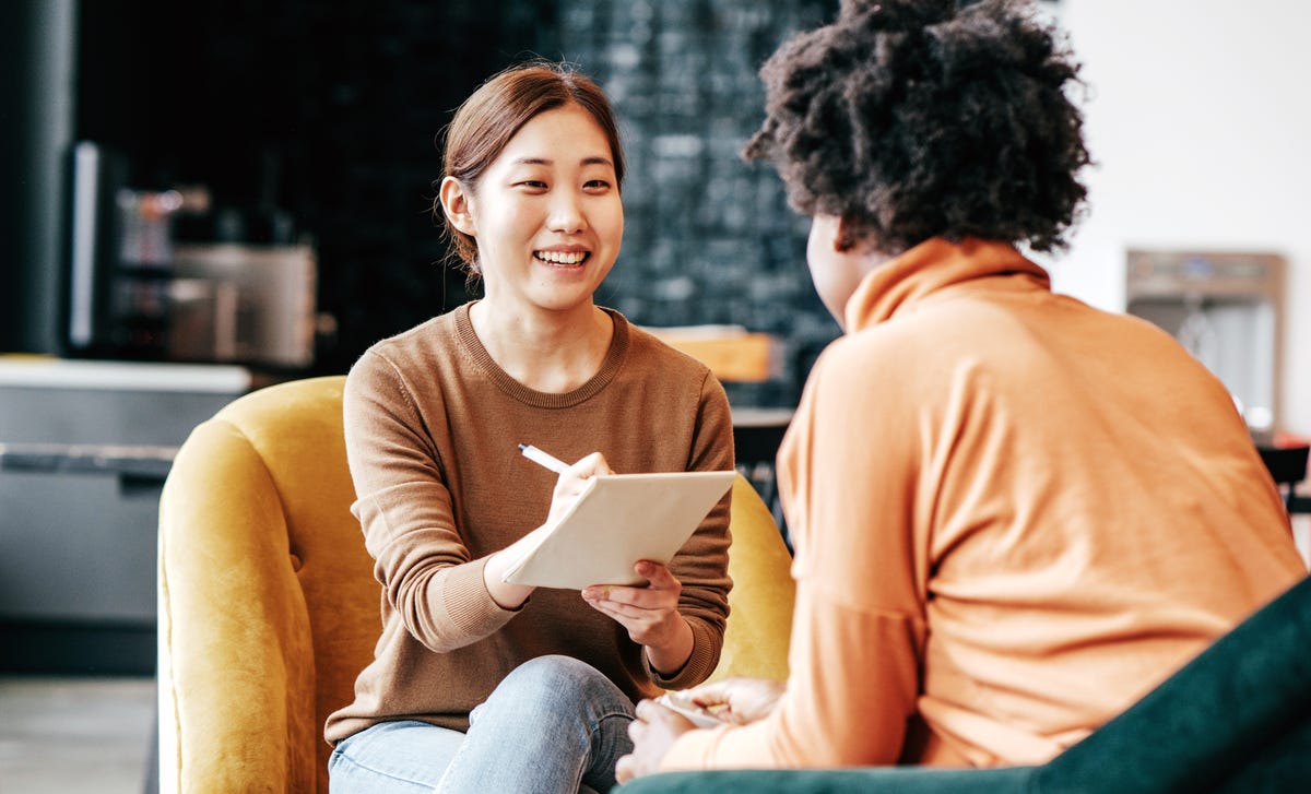 Students making notes while talking to her instructor during an intensive English lesson