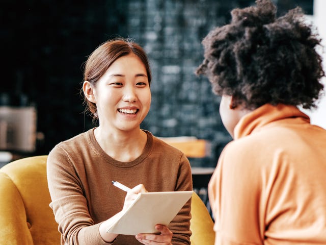 Students making notes while talking to her instructor during an intensive English lesson
