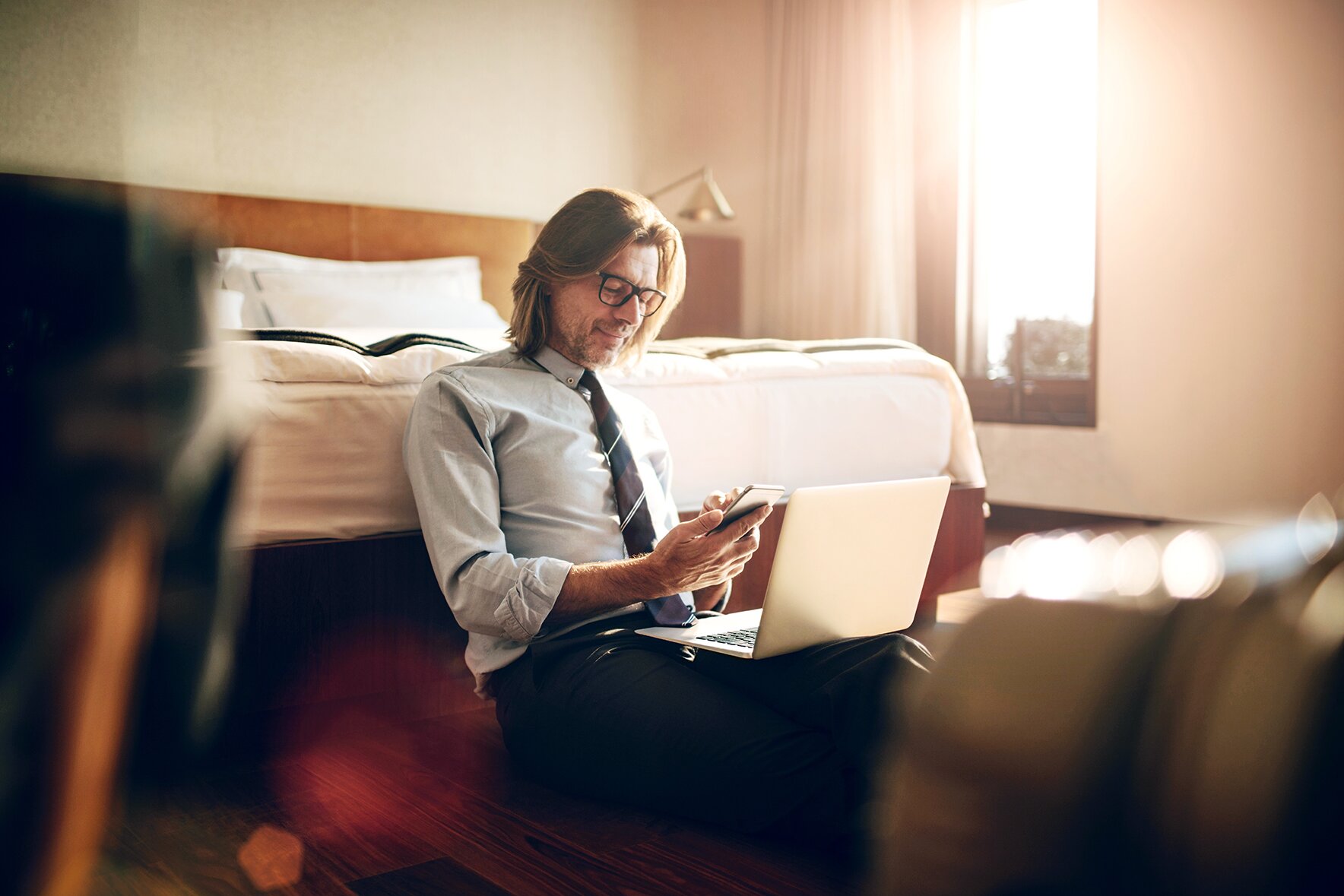 Un homme assis à côté de son lit, un ordinateur portable sur les genoux, suit un cours d'anglais á Marseille.