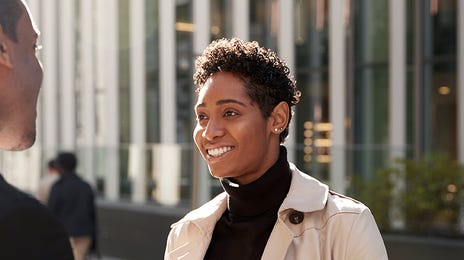 Femme tenant une tasse de café et discutant avec son amie à l'extérieur d'un bâtiment après son cours de TOEFL préparation avec Berlitz.