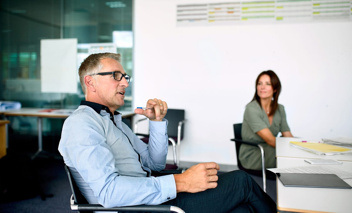 Homme et femme d'affaires assis à une table et discutant de l'empreinte.