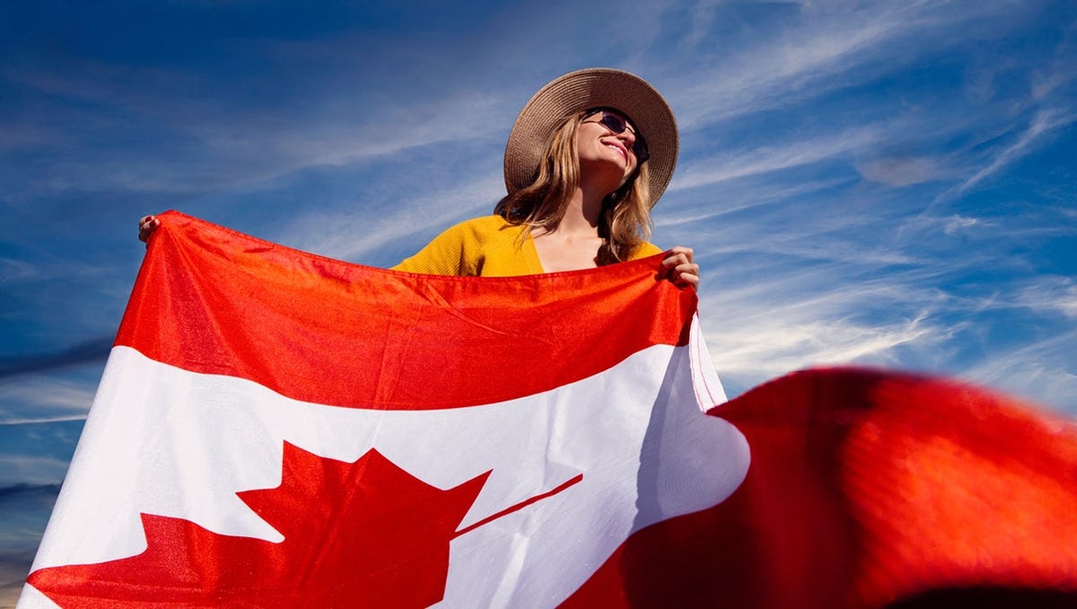 Woman in a straw hat hand and sunglasses waving the flag of Canada