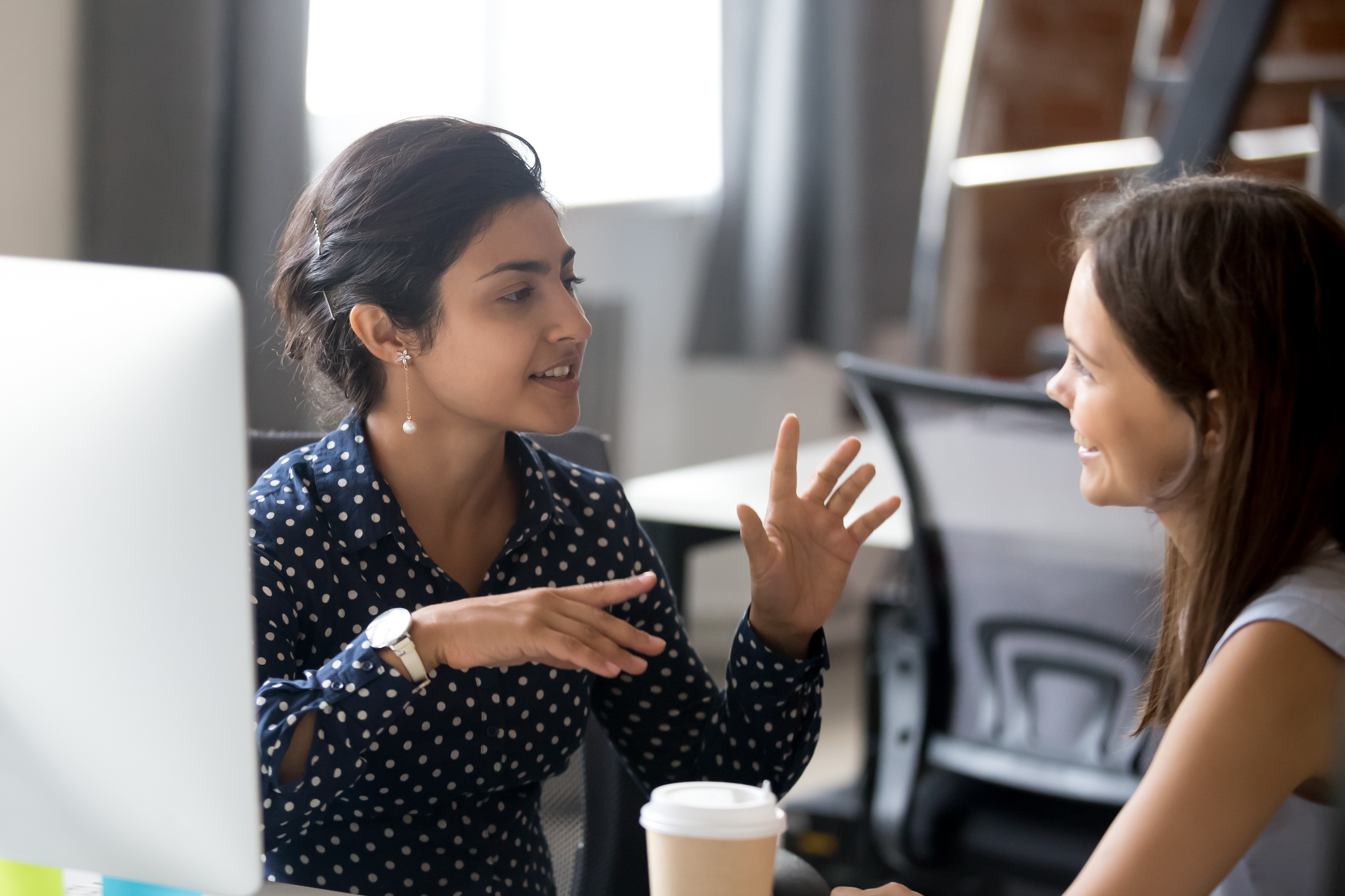 Femme assise à côté d'un ordinateur parlant à son formateur dans une langue étrangère lors d'un apprentissage intensif de la langue