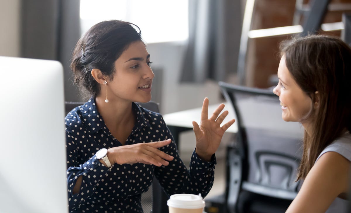 Femme assise à côté d'un ordinateur parlant à son formateur dans une langue étrangère lors d'un apprentissage intensif de la langue