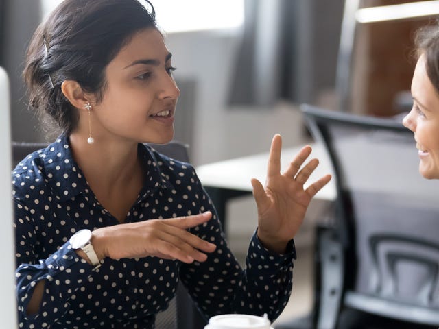 Femme assise à côté d'un ordinateur parlant à son formateur dans une langue étrangère lors d'un apprentissage intensif de la langue
