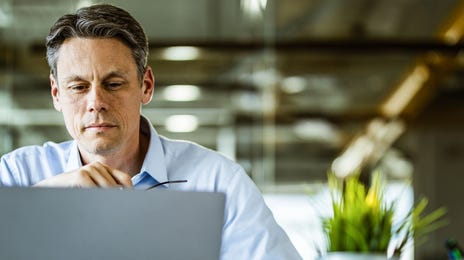 Homme devant un ordinateur portable lisant Berlitz prix des cours
