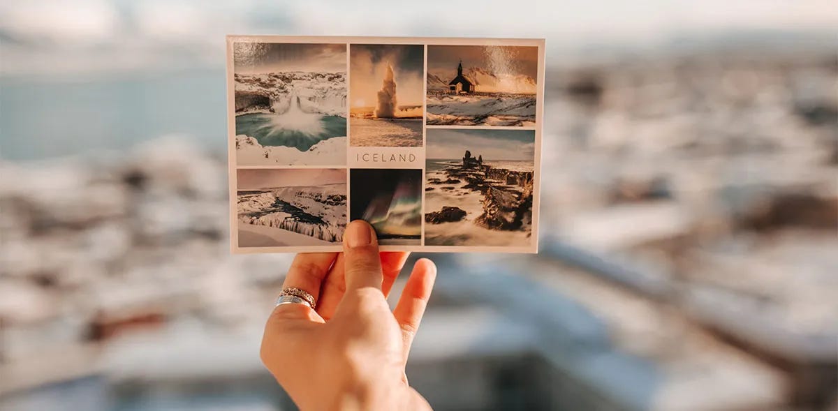 A hand holding up a postcard from Iceland