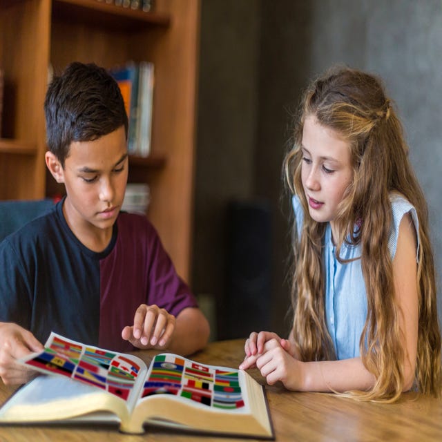 Boy and girl looking at flags in a book during an English class for kids and teens with Berlitz
