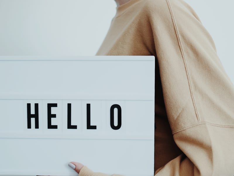 Woman holding a board that shows a text saying "HELLO"