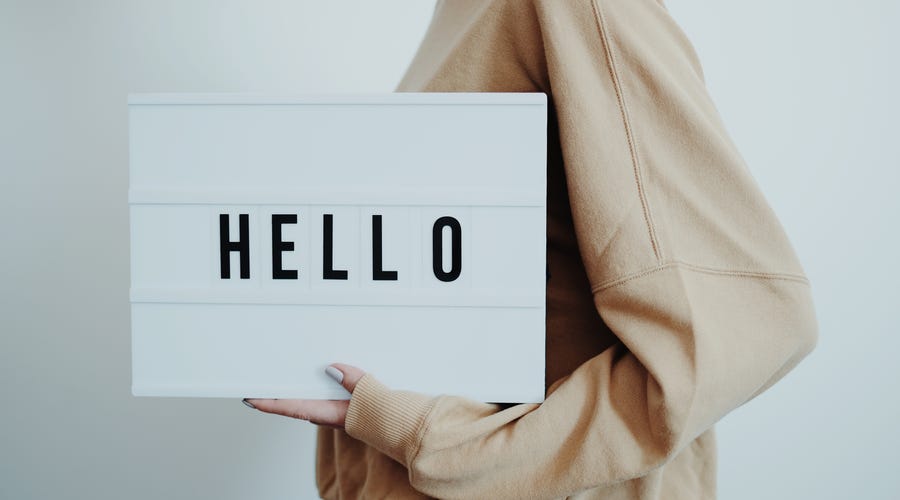 Woman holding a board that shows a text saying "HELLO"