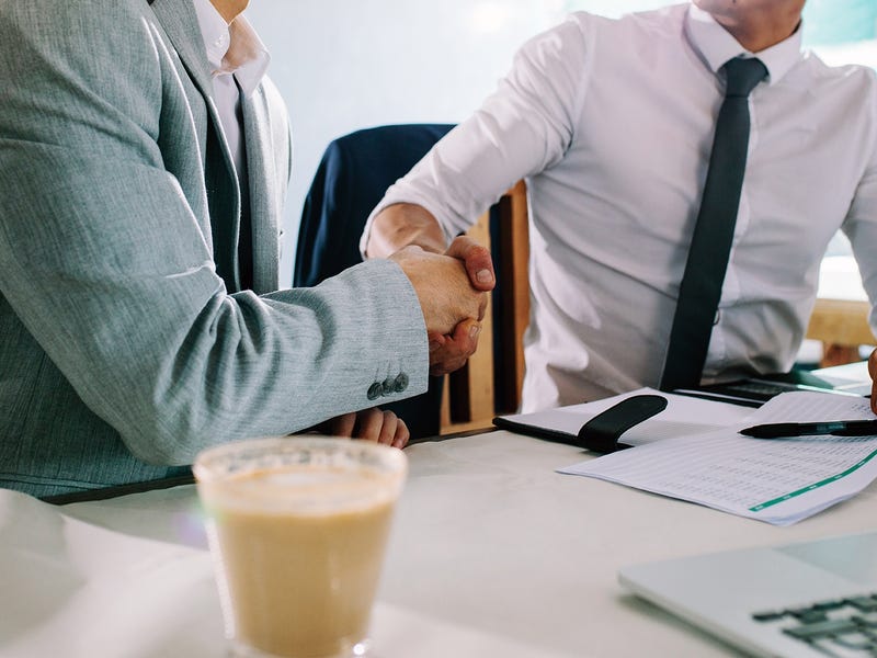 Two businessmen shaking hands and thanking each other for coming to a meeting