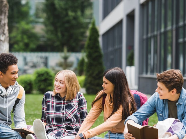 Groupe d'adolescents assis dans un parc et discutant pendant leur colonie de vacances anglais