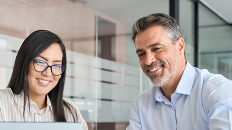 Deux employés devant un ordinateur portable discutent entre eux après leur accompagnement expatriation.