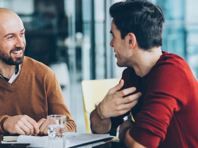 Deux hommes assis à une table avec des papiers et parlant de Berlitz Corporation