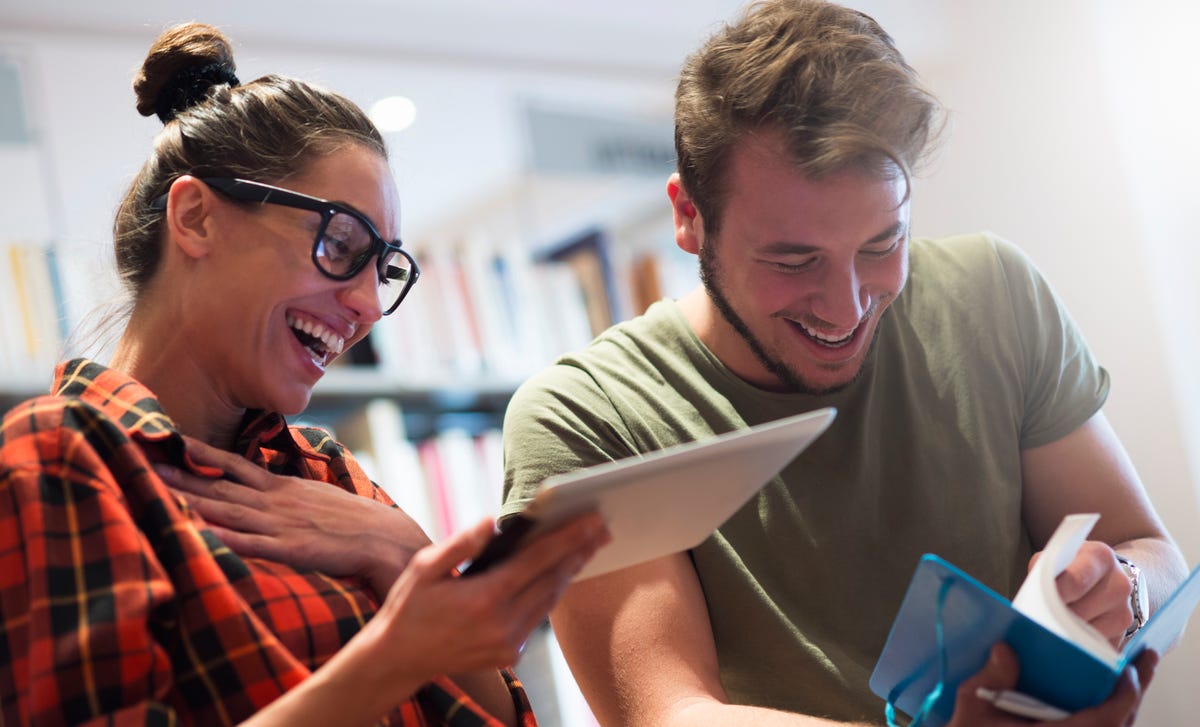 Students showing each other something on a tablet and laughing during an English class with Berlitz France