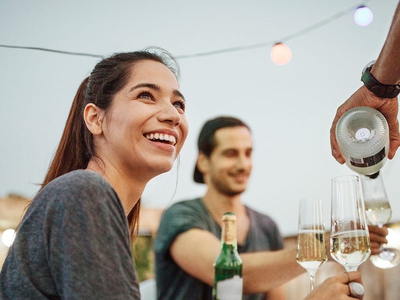 Femme à l'extérieur d'un restaurant mangeant avec ses amis et disant bonjour en allemand au serveur
