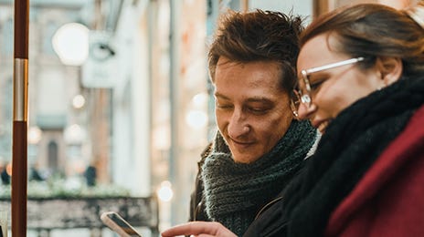 Woman holding a phone and showing to his friend how he can use subsidized courses with Berlitz France