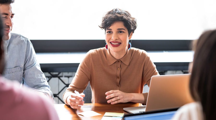 Woman with a laptop and sticky notes talking to her language instructor about interrogative words in English