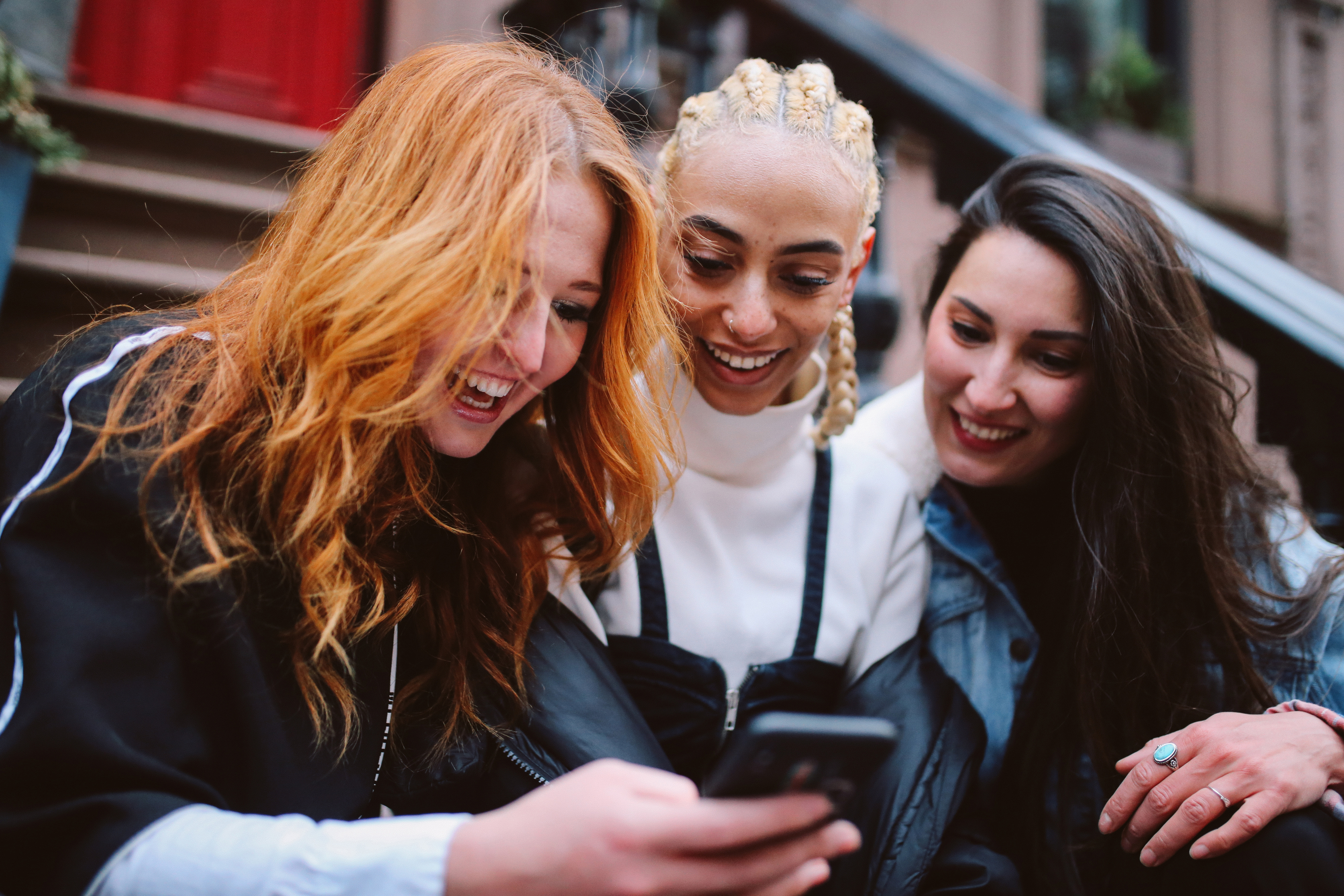 Des filles regardent un téléphone et lisent des informations sur le fonctionnement de Berlitz tout en souriant et en se parlant.