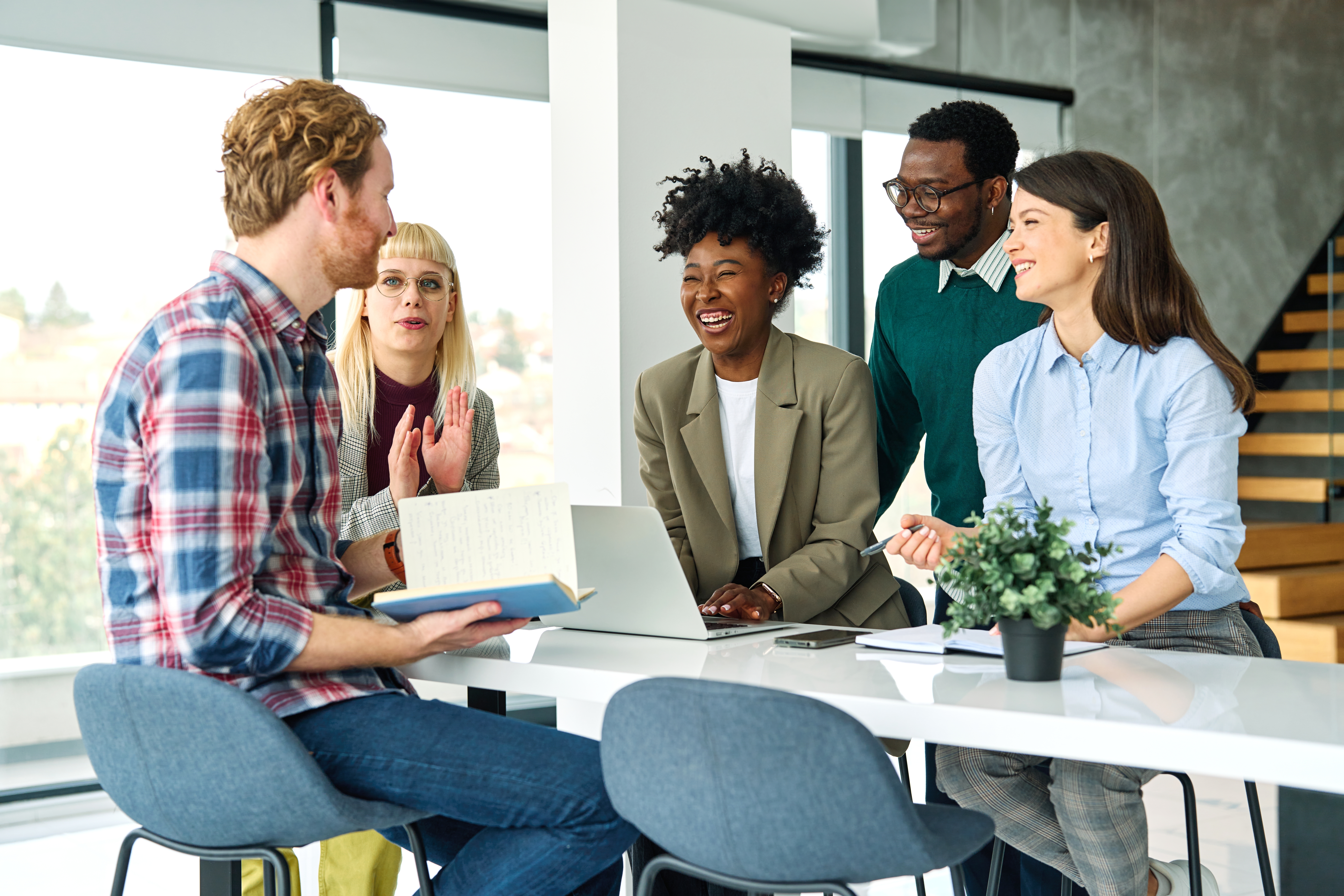 Étudiants entourant leur professeur et riant de sa plaisanterie après leur cours de langue en groupe.