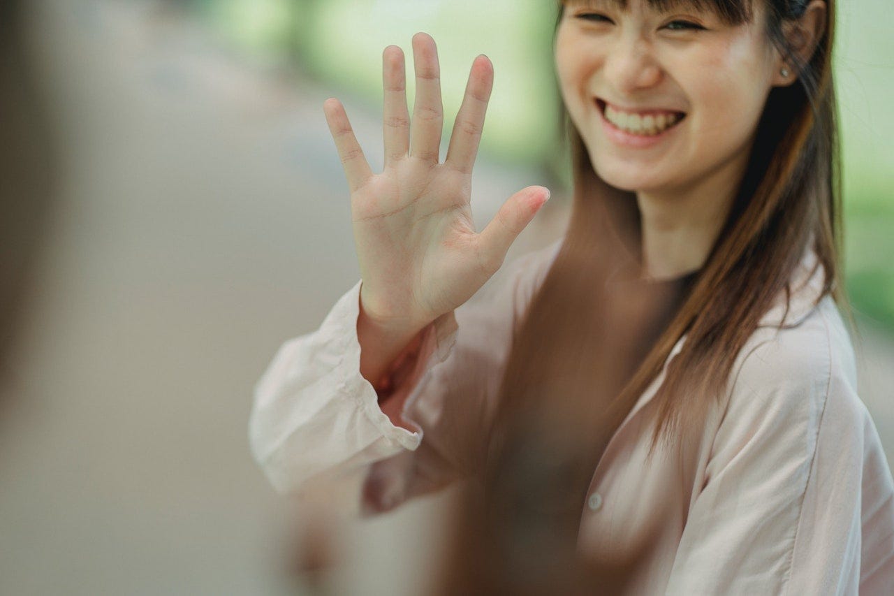 Woman waving and and smiling at her friend while saying hello in German