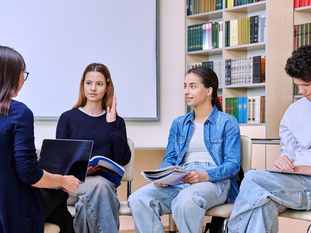 Un groupe d'étudiants adolescents assis sur des chaises en cercle avec leurs notes et discutant avec leur professeur lors d'un sejour linguistique ado