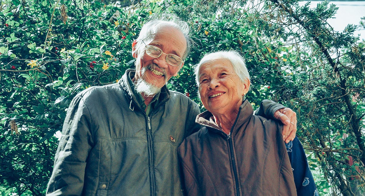 Elderly man and woman hugging each other and smiling in a garden