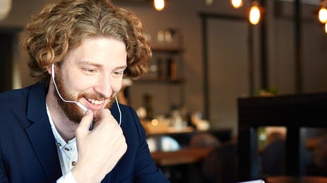 Man in headphones attending an Online English class with Berlitz Grenoble from a coffeeshop