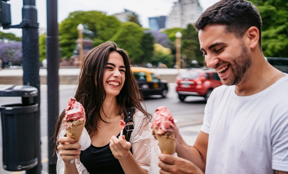 Man and woman walking on a street eating ice cream after their Spanish class with Berlitz France.