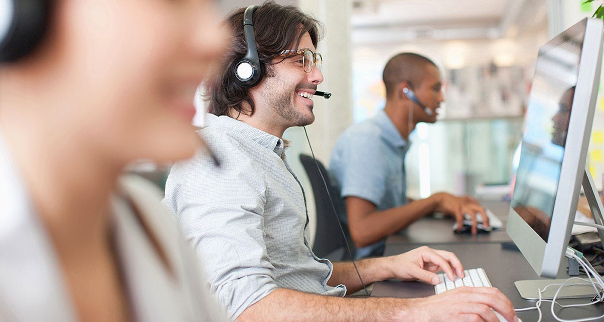 A group of salespeople sitting at their desk talking to their customers online wearing headphones