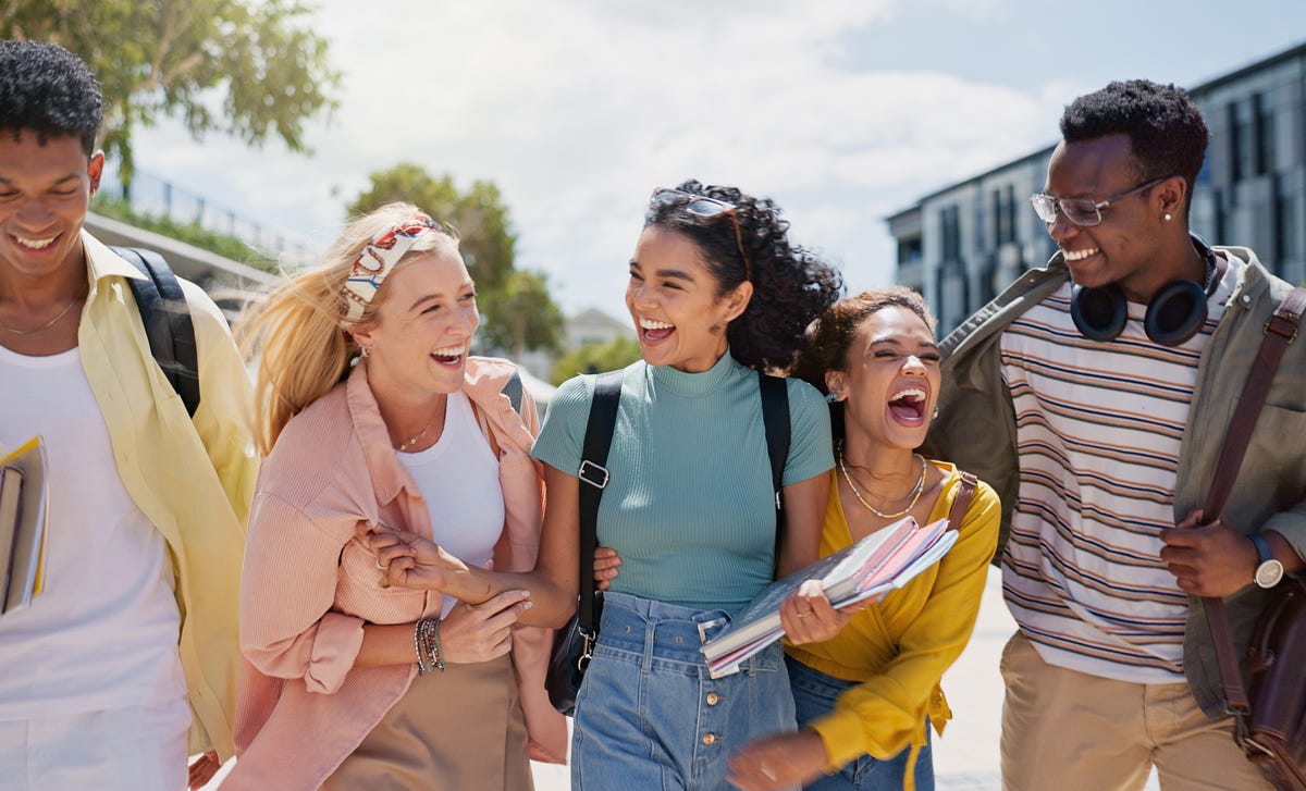 Des adolescents avec des sacs à dos et des blocs-notes discutent et rient en se rendant à leurs stage anglais vacances