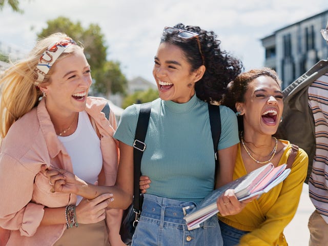 Des adolescents avec des sacs à dos et des blocs-notes discutent et rient en se rendant à leurs stage anglais vacances