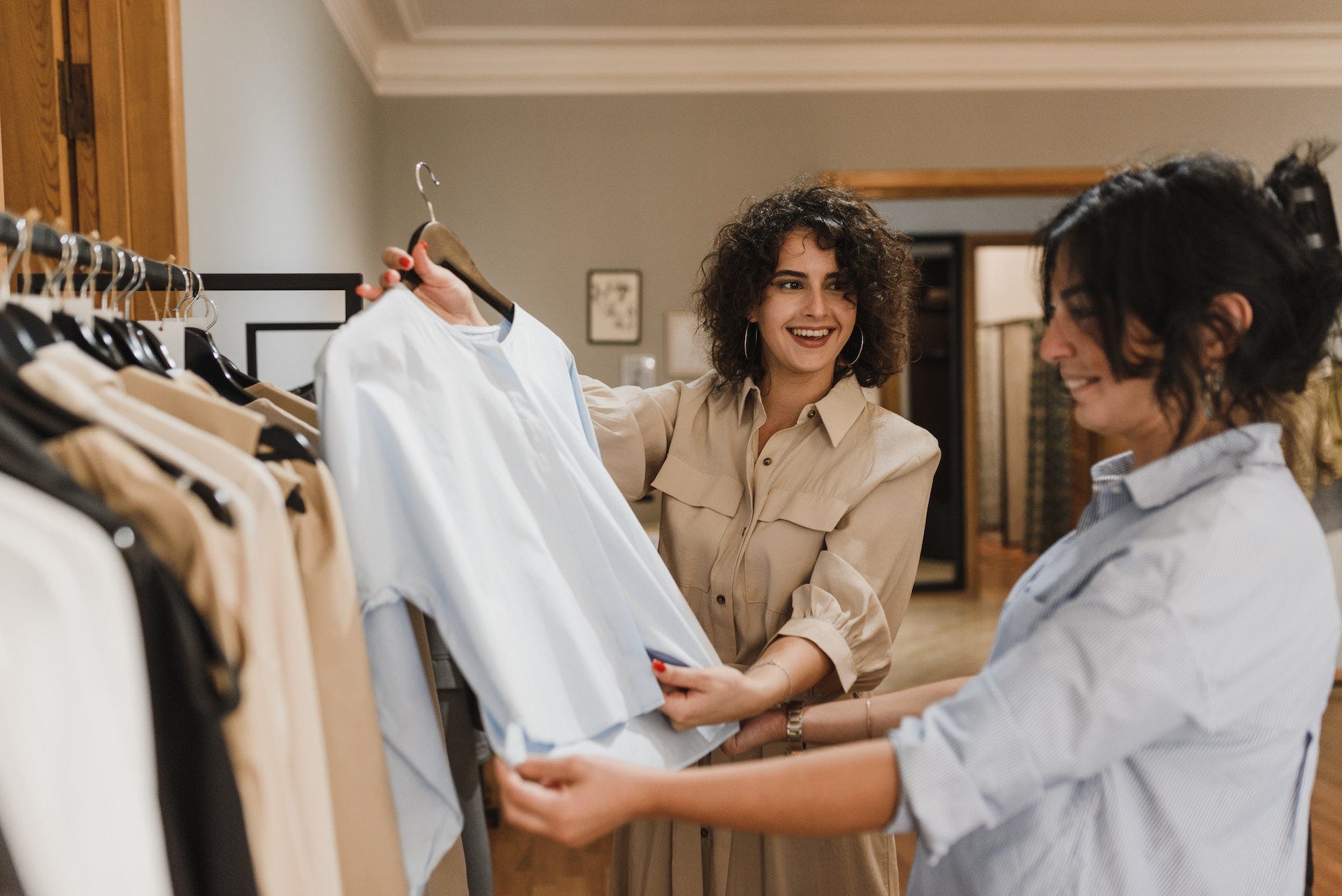 Woman in a clothes store asking her friend if she likes the shirt in her hand