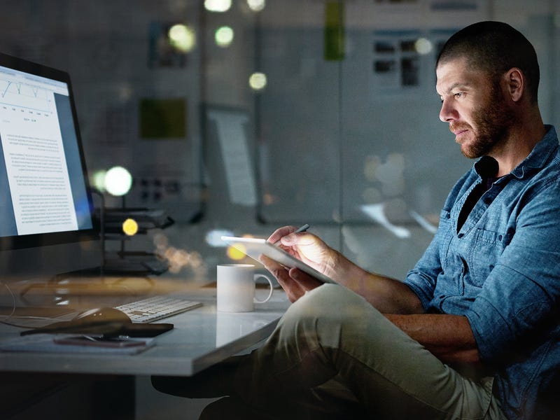 Homme devant un ordinateur tenant un cahier et écrire lettre ou email en anglais