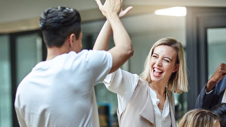 Des employés participant à un formation en entreprise se réjouissent de la réussite de l'autre et se félicitent mutuellement.