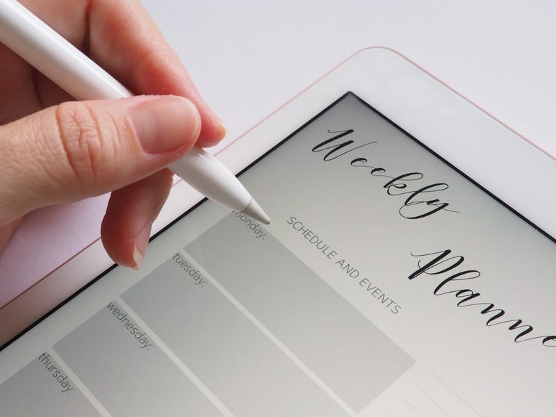 Une main écrit dans un semainier sur une tablette et planifie les jours de la semaine en espagnol