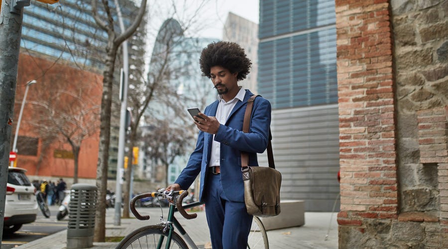 Homme poussant son vélo et lisant les niveaux d'anglais sur son téléphone