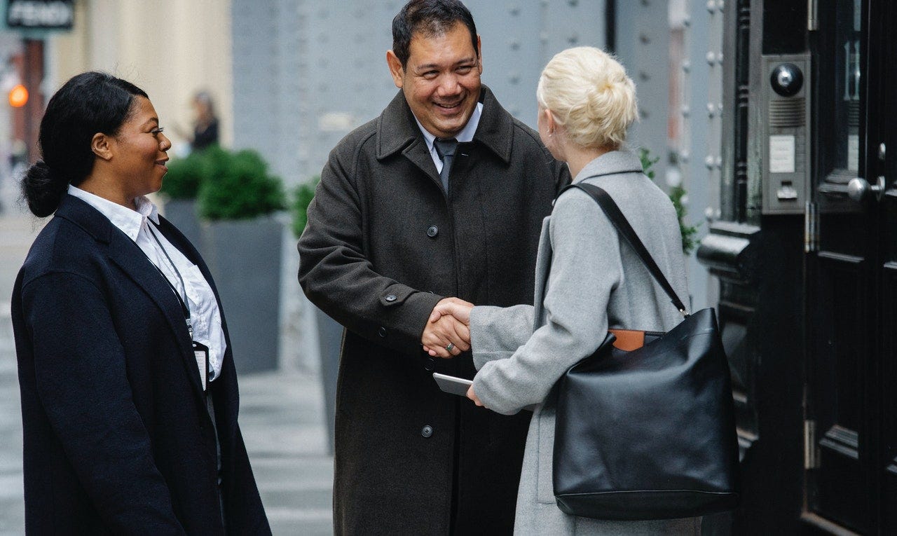 Colleagues shaking hands and greeting each other in German on the street