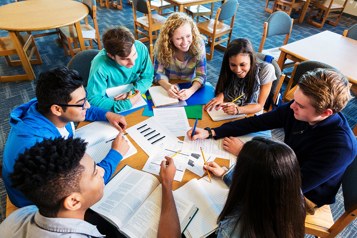Kids and their instructor sitting around a table with their papers and talking during a camp
