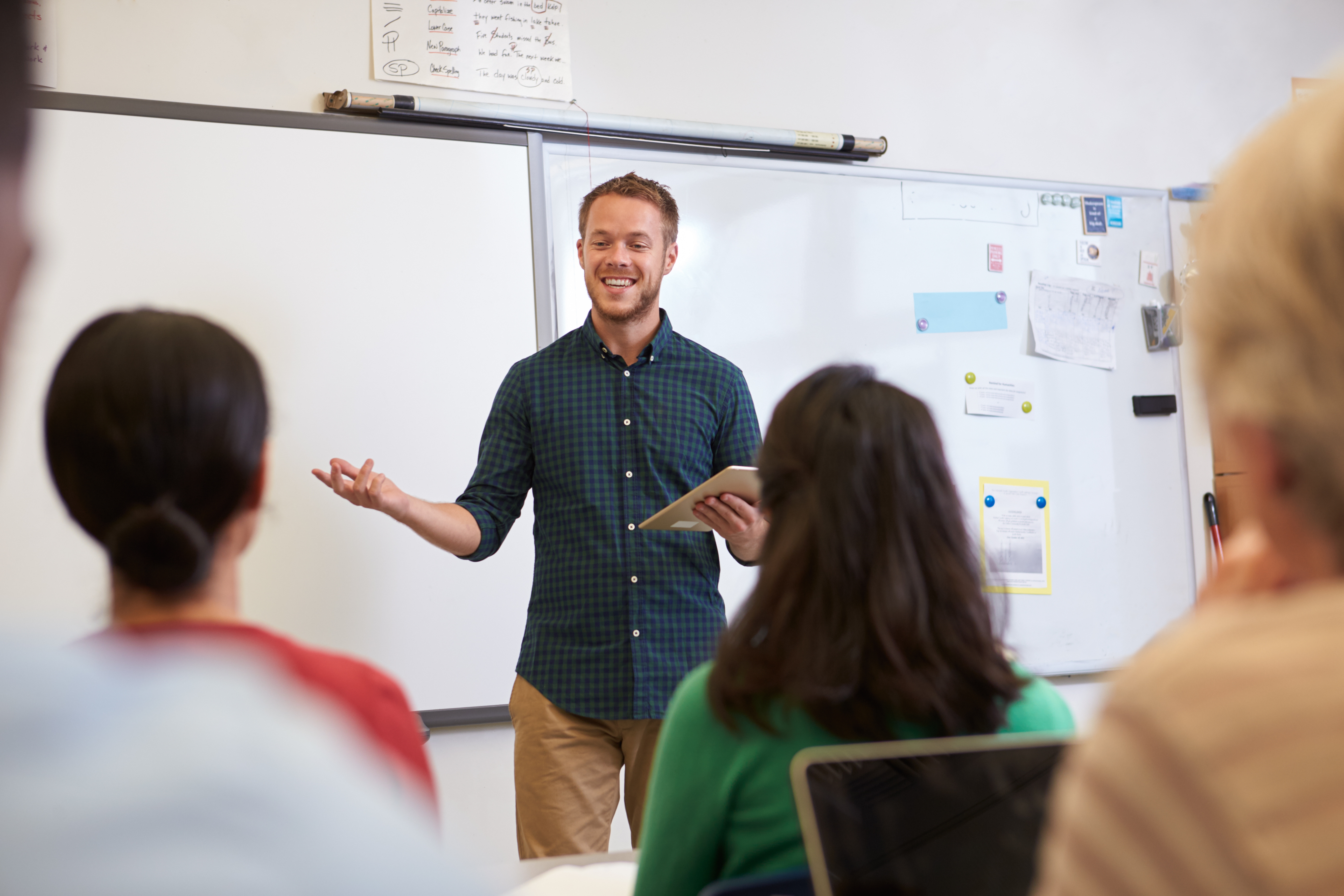 Professeur devant un tableau blanc s'adressant à ses étudiants qui suivent des cours de langue avec lui