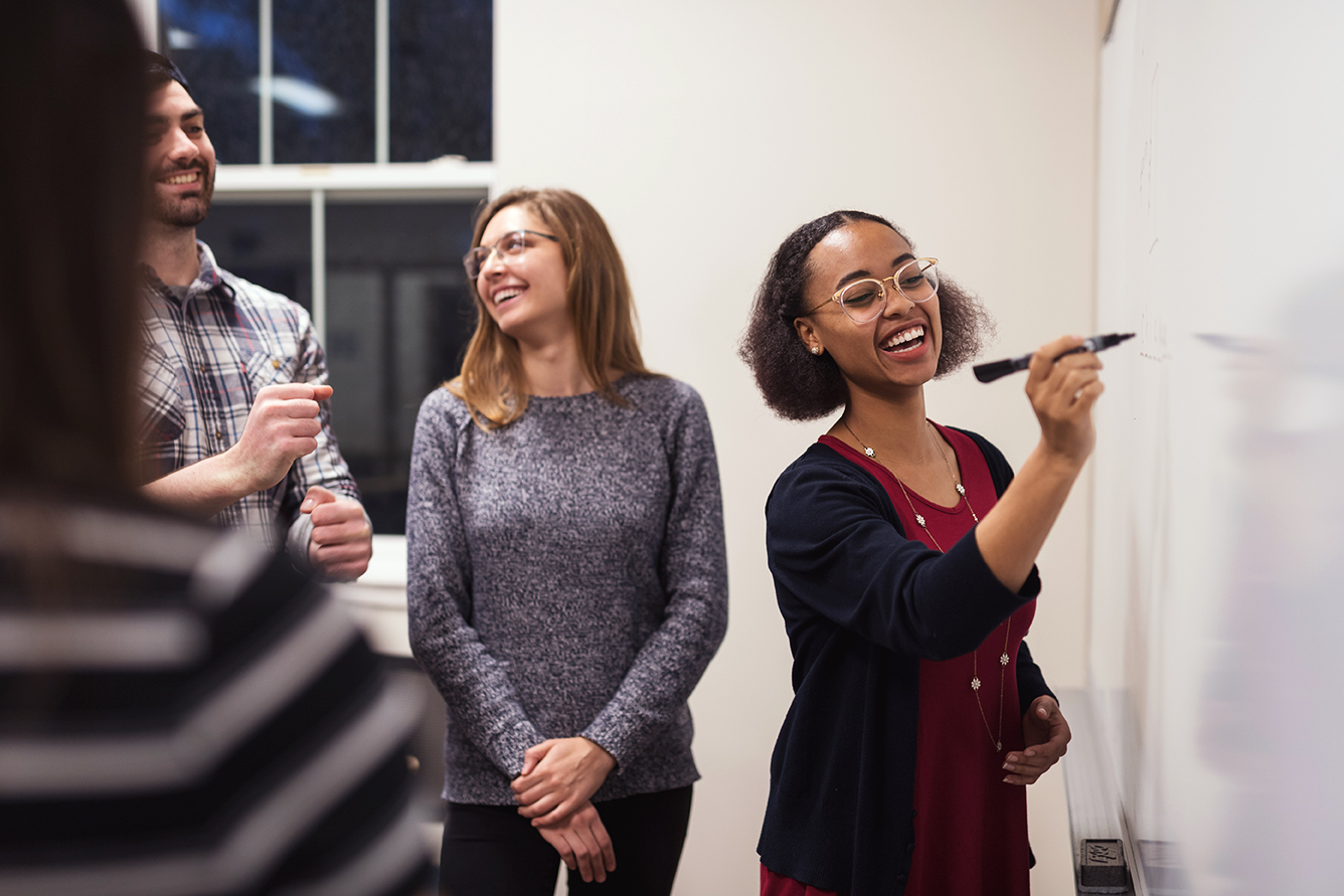 Students talking and writing on a whiteboard during a language class with Berlitz in a coworking space.