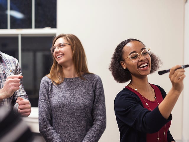 Students talking and writing on a whiteboard during a language class with Berlitz in a coworking space.