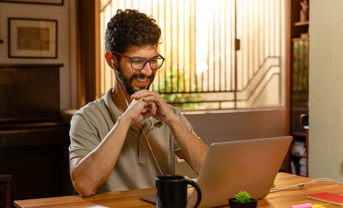 Man with headphones sitting in front of his laptop in his room and attending an online Italian lesson with Berlitz France