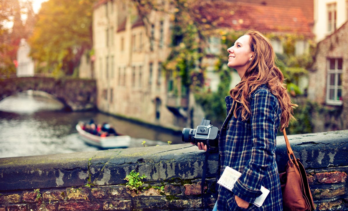 Femme avec un appareil photo se tenant sur un pont et observant la ville