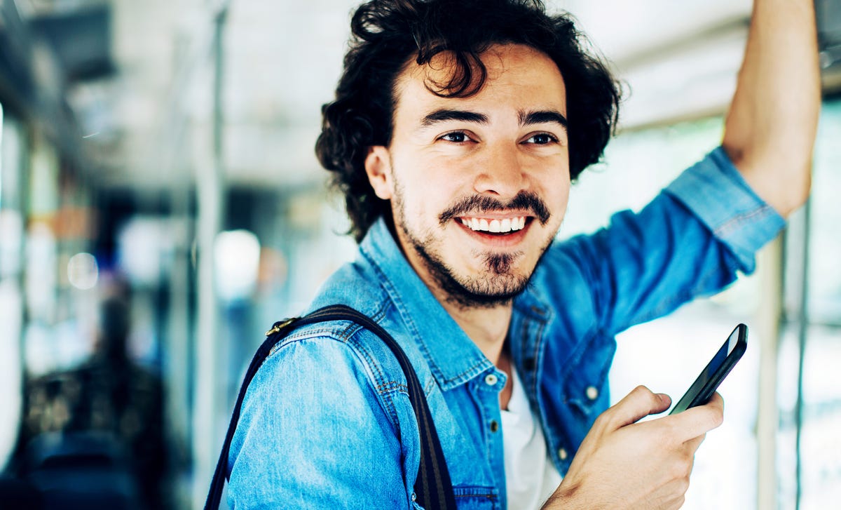 Homme dans les transports en commun tenant son téléphone sur le chemin de son cours d'allemand pour débutant avec Berlitz France