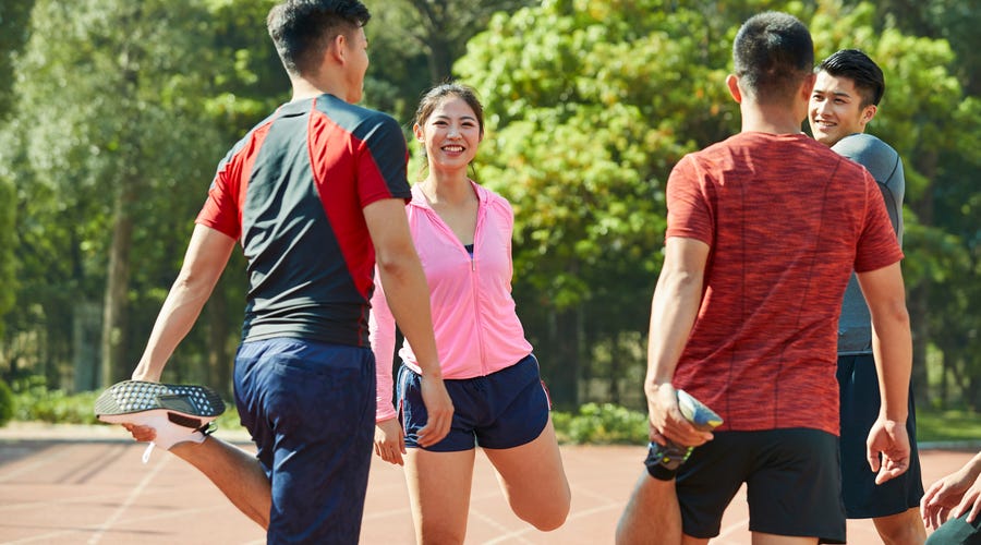 Un groupe d'amis dans un parc échauffe ses muscles pour faire du jogging après avoir appris à connaître les corps humain en anglais