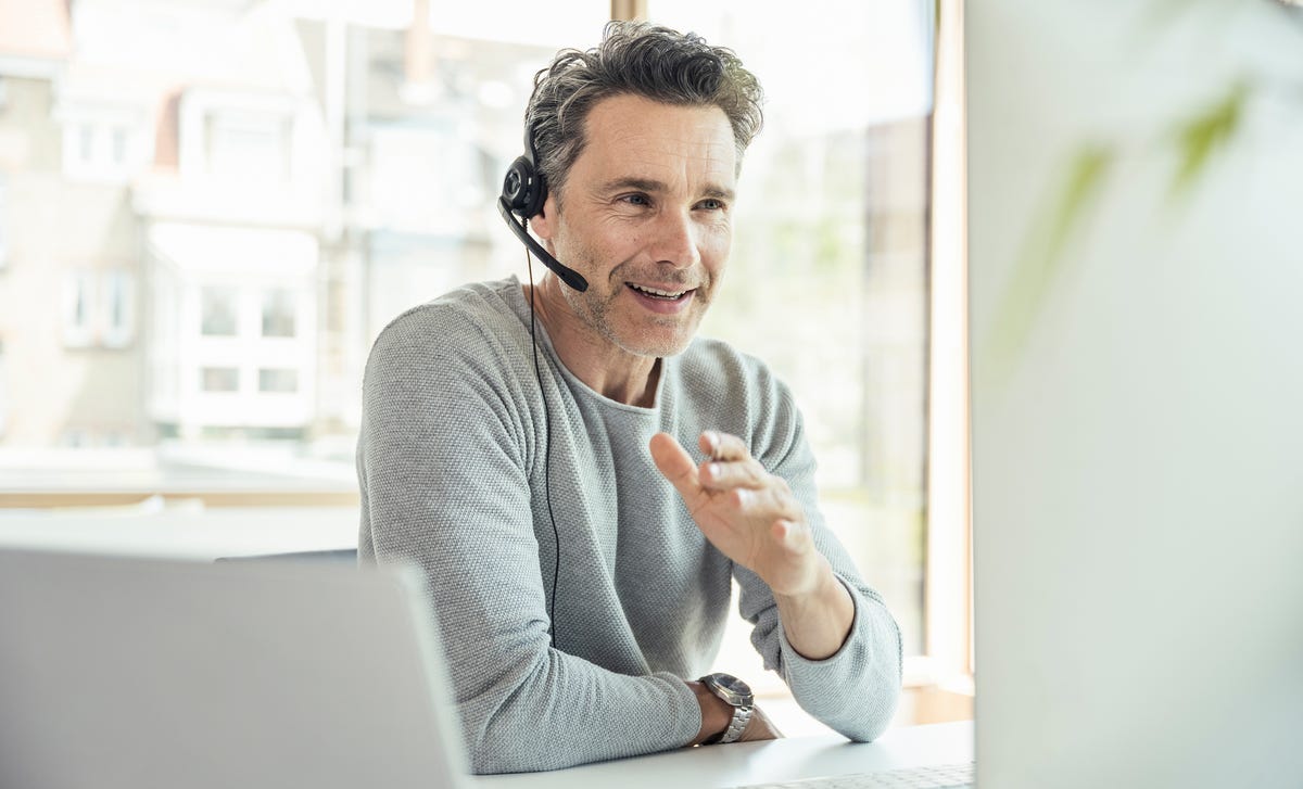 Homme portant un casque qui suit un formation d'anglais en ligne avec Berlitz France depuis son ordinateur et qui parle à son formateur.