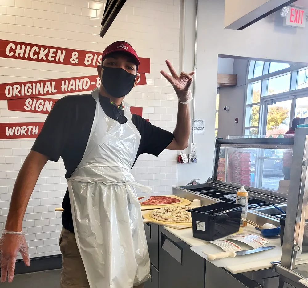 Young employee posing while making hand made pizzas