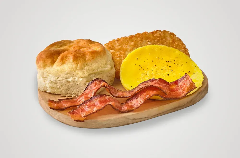 Breakfast Basket containing a biscuit, egg, two slices of bacon, and a hasbrown.