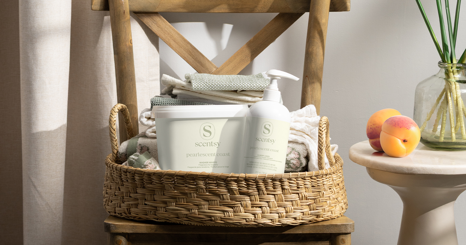 Productos de lavandería Scentsy exhibidos en una canasta tejida con ropa doblada en un ambiente hogareño natural y suave.